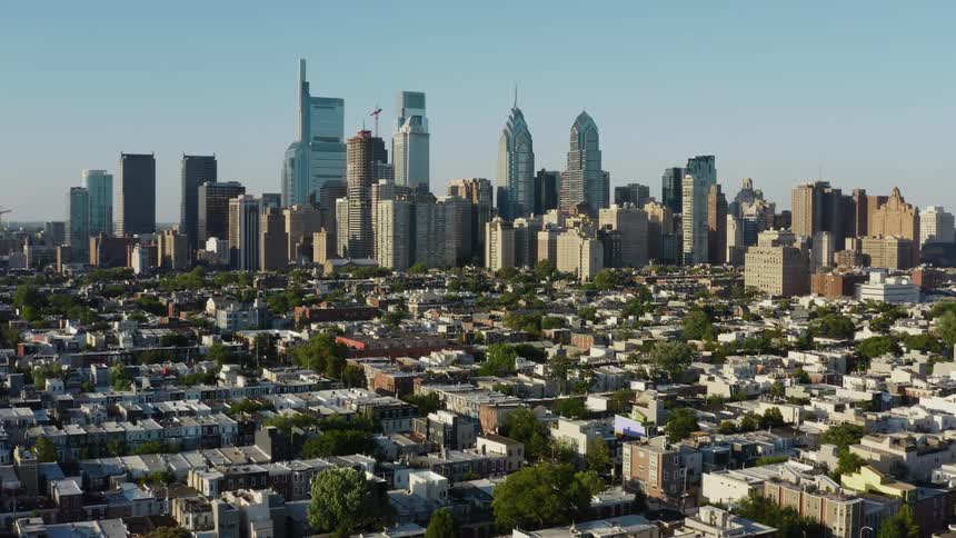 A tower block in a city in the distance with surrounding neighborhoods down below during the day