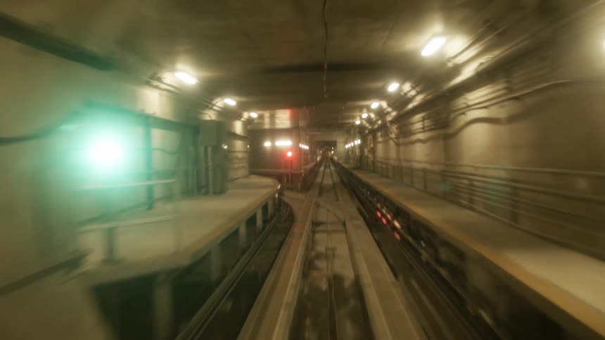 Underground subway tunnel forks at intersection with colored light