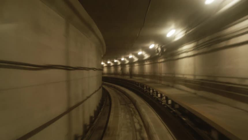Subway tunnel is lit by ceiling lights and bordered by pedestrian walkway