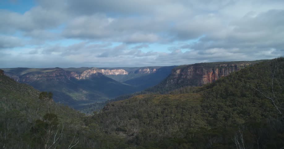 An enormous canyon landscape is covered in forests as clouds slowly pass overhead