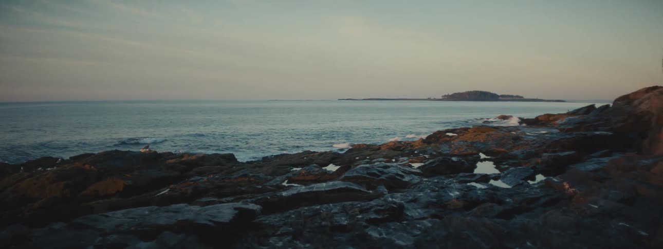 Waves gradually break against the rocky shoreline of a coastal area