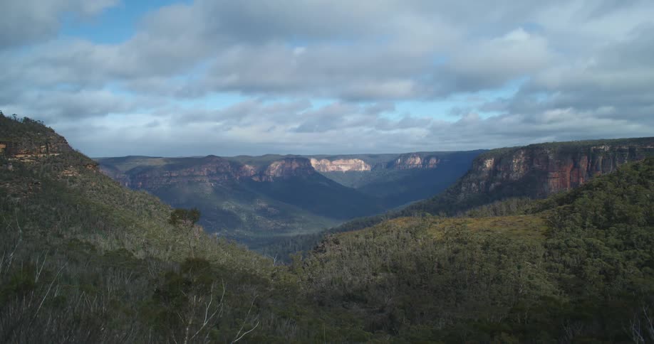 Tree covered hills and cliffs under a cloudy sky