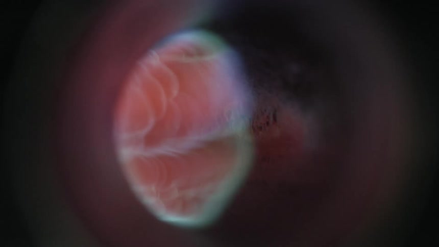 A pulse of a pink color flashes through a small funnel in pitch black