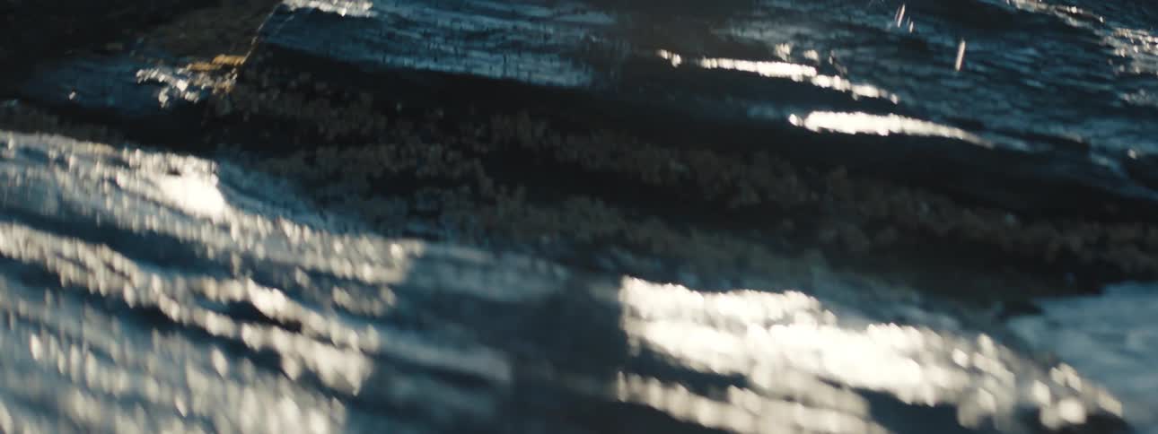 A person walks through puddles alongside a river
