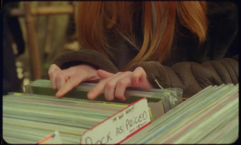 A woman with a coat looking through records
