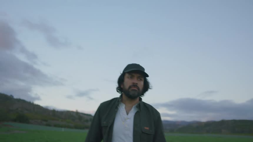A man walking out in a farm field at sunrise