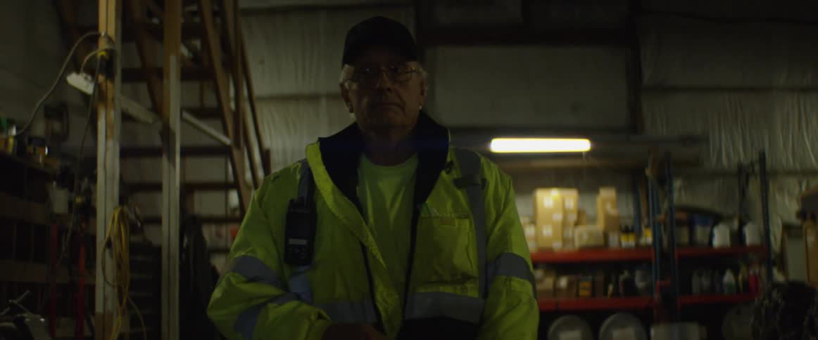 Man walking inside a warehouse zips up his jacket