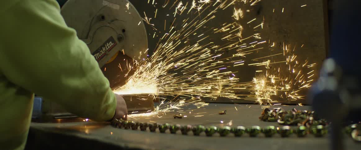 A man using a large buzz saw on a table inside of a warehouse