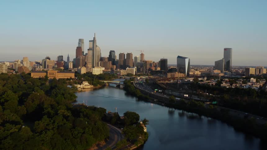 Traffic drives down a road that aligns with a river leading to downtown Philadelphia