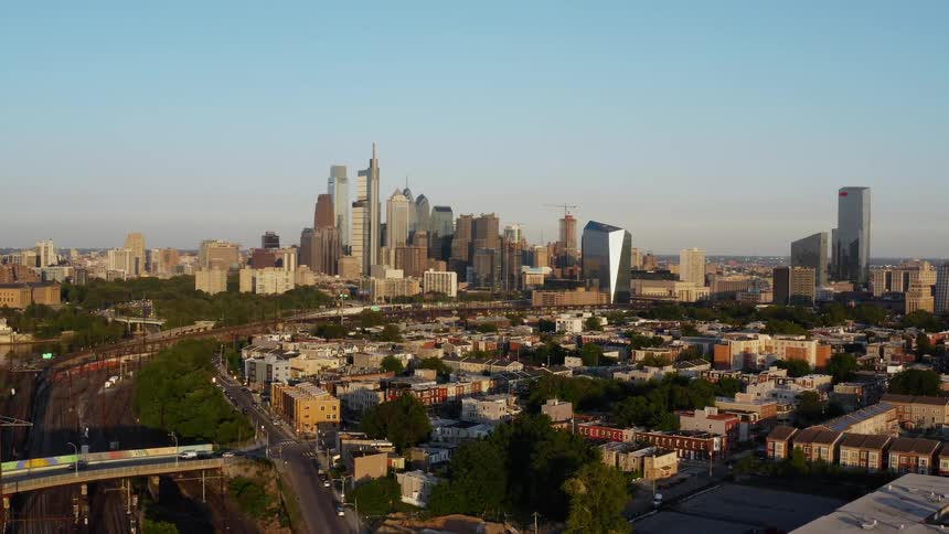 Skyscrapers and buildings in Philadelphia with traffic traveling on the city streets under a blue sky