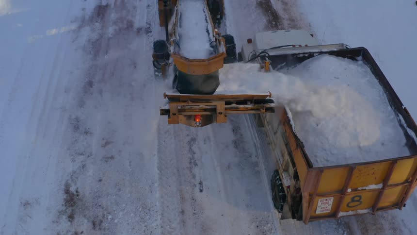 Tractor and truck removing snow from a rural road in the countryside at morning