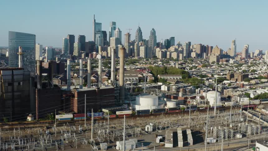An aerial view of a factory in a city with the skyline behind it
