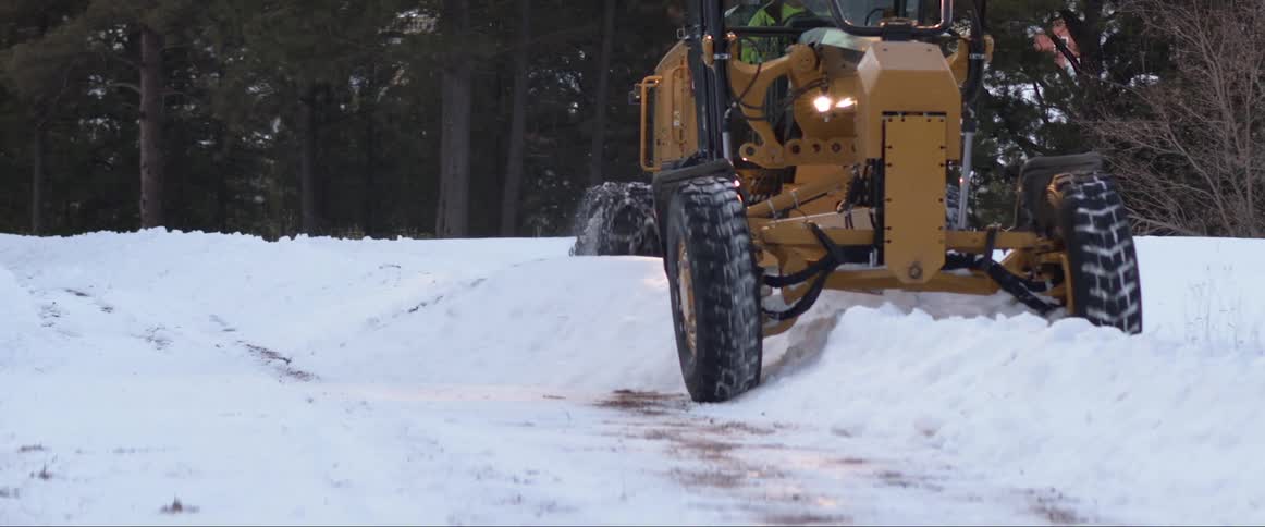 Tractor plowing snow on a road in the countryside at morning
