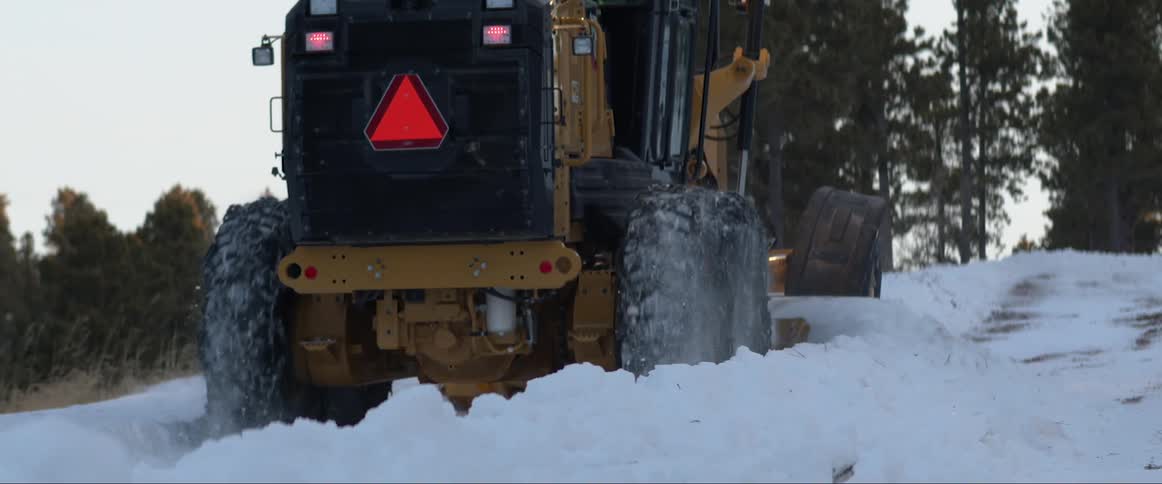A snow plow plowing snow on a hill