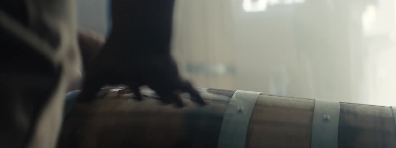 A person in a room rolling a barrel with a wall and window in the background