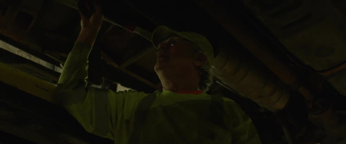 Man wearing a hat shines a flashlight on the pipes in the ceiling