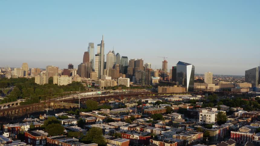 Cars travel on city highways with neighborhoods on one side and a towering city skyline on the other in Philadelphia