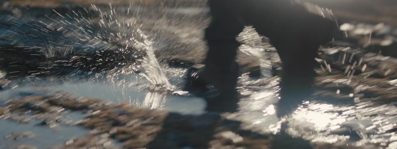 A person walks through puddles next to a river