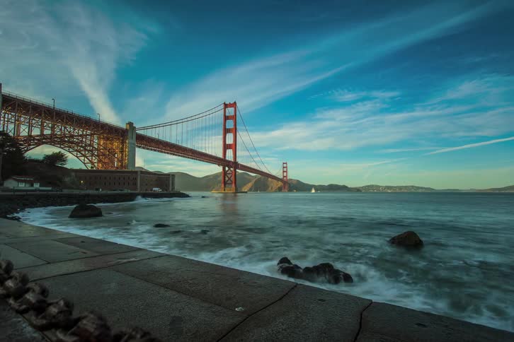 Time lapse of water hitting a pier near a bridge