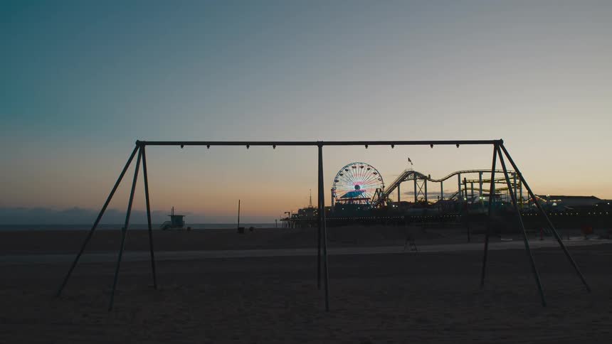 A beach with sand with an amusement park the sky and clouds in the background