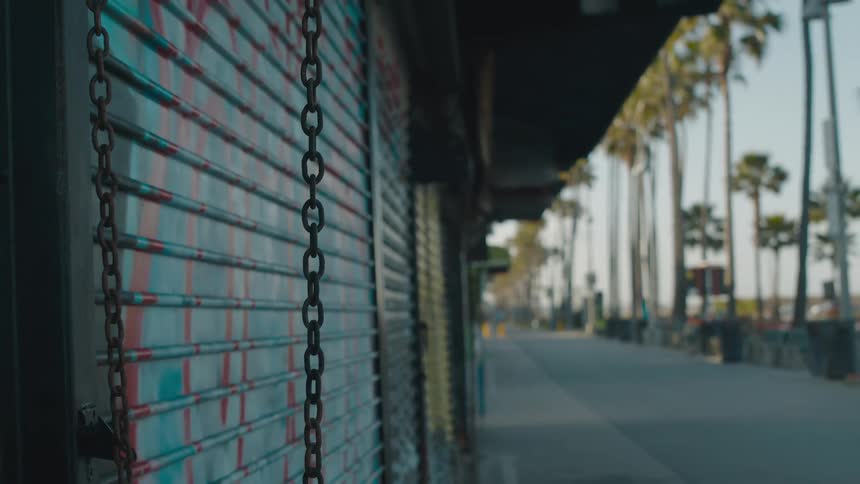 A pair of chains hang in front of a metal door on a building next to a walkway