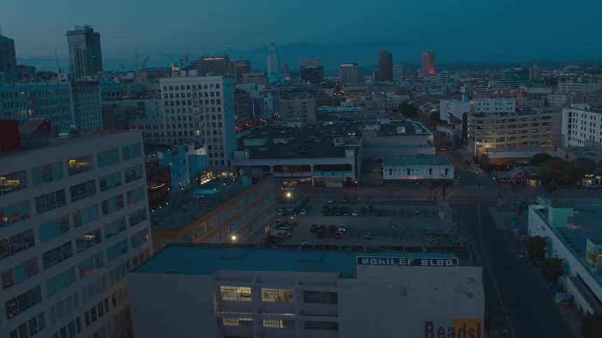 Lights glow in windows and on the street of a city at dusk