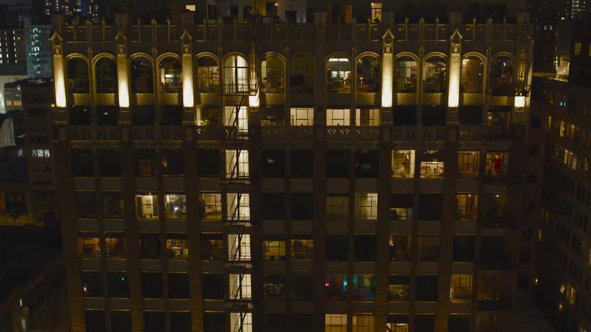 Passing traffic reflects onto the windows of a tall apartment building