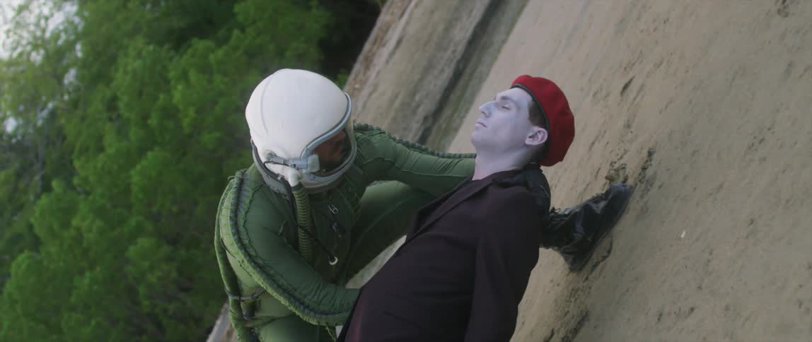 An astronaut places a pale dead body on the beach