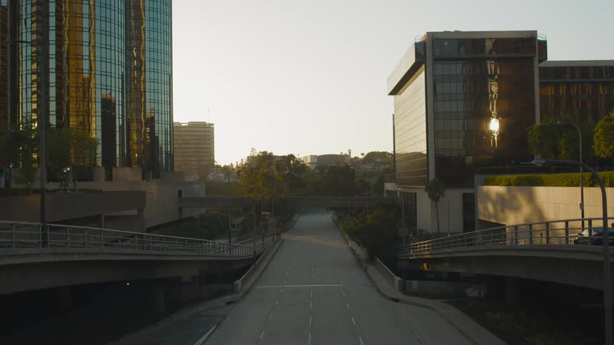 Emptyroad passes between reflective glass covered skyscraper and lower building