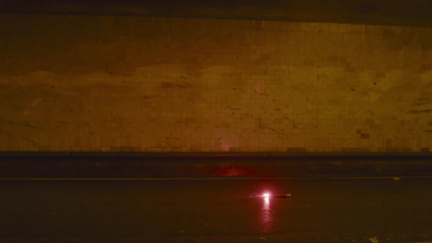 A burning stick on the ground in front of a wall