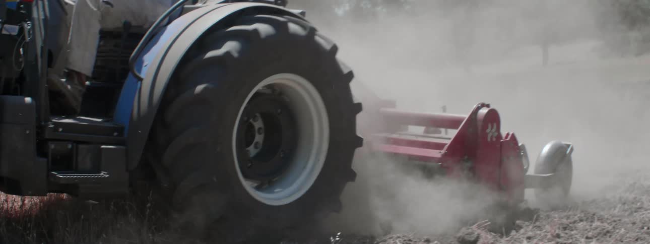 A person is working the field with a tractor