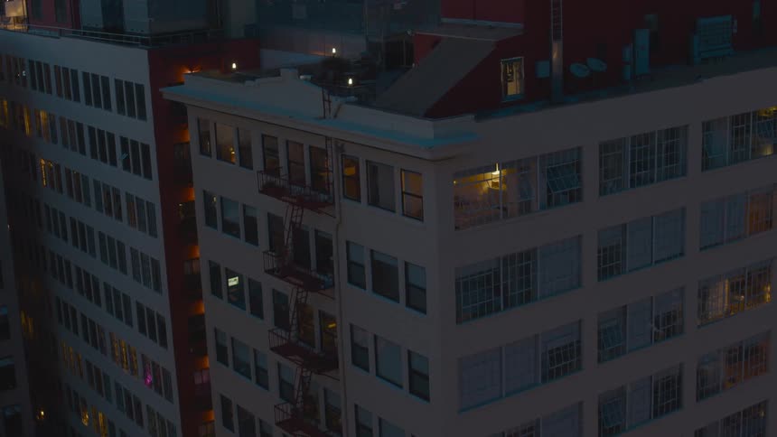 An aerial view of a building in a downtown city is displayed at night