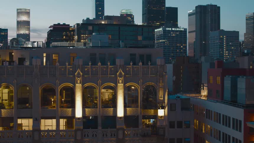 As the sun is setting a number of tall buildings in an urban area are illuminated
