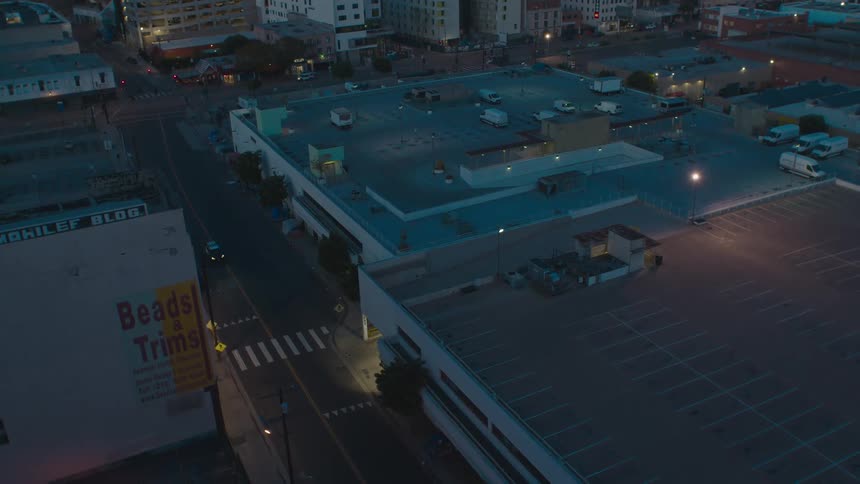 Vehicle drives along street at night past parking garage