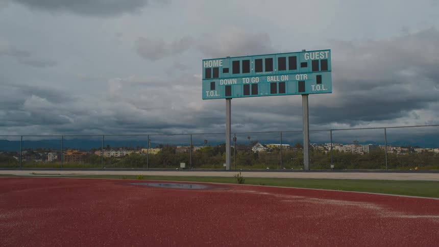 Dark storm clouds behind a scoreboard in a sports stadium
