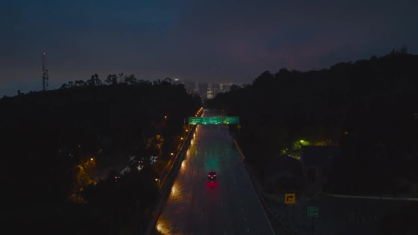 Cars pass along a large freeway as they head towards a city in the distance