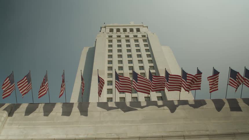 Several american flags in the wind above the entrance to a building