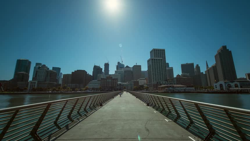 Time-lapse of people walking along a pier near a city