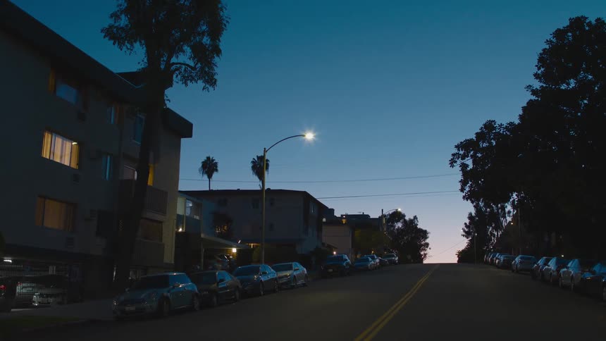 Cars are parked near a building in a downtown city at night
