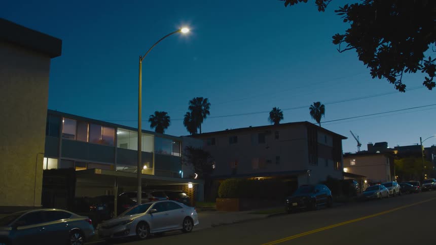 Cars parked on a street in front of an apartment building at night