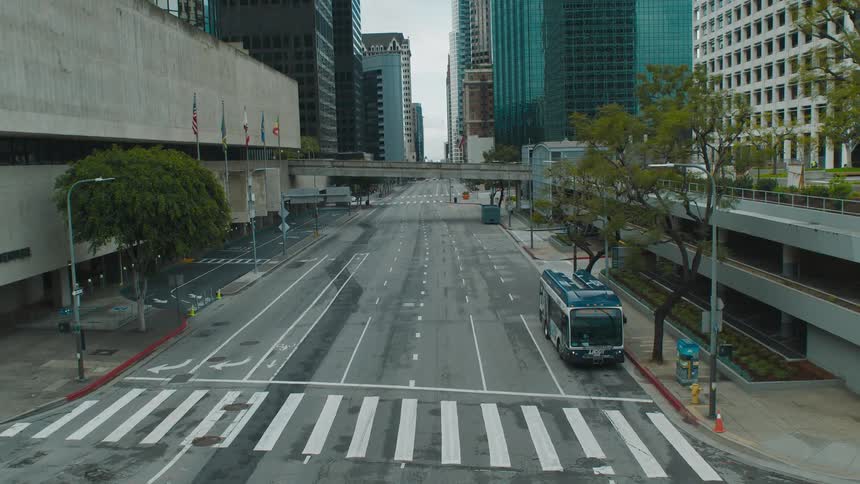 Bus stands with blinking lights at sidewalk next to building downtown