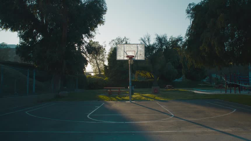 The sun is rising on the park as a person walks by