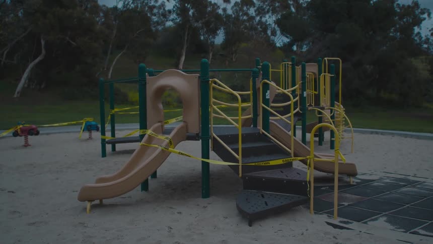A playset covered in warning tape on a playground in the evening