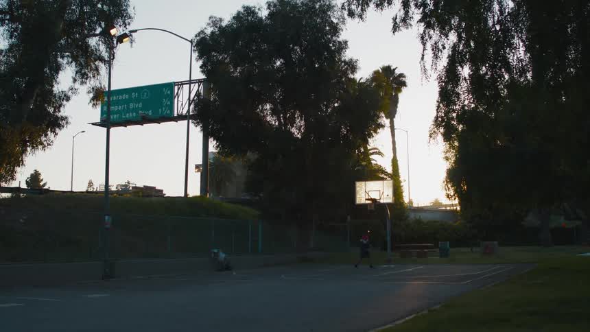 A person is practising basketball outside near a freeway