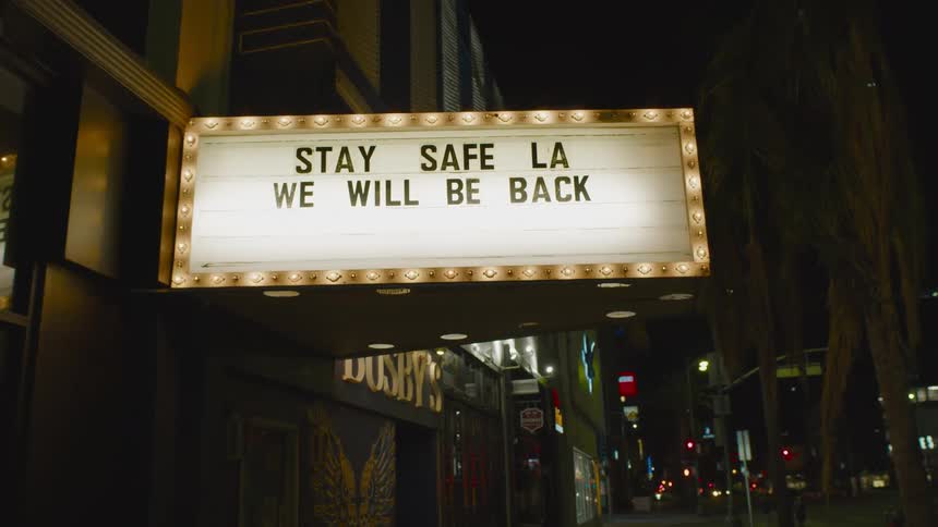 A lit up sign flashing on a business flashing on a city street