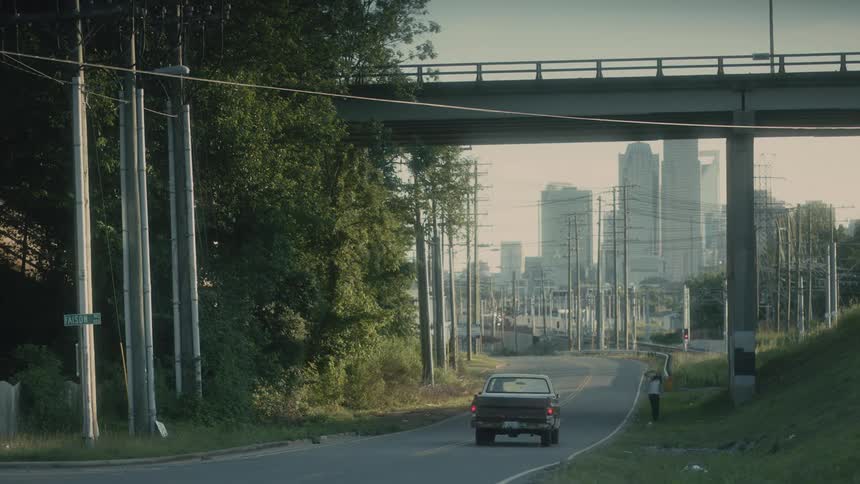 A pickup truck headed toward downtown pulls over to talk to a hitchhiker on the side of the road