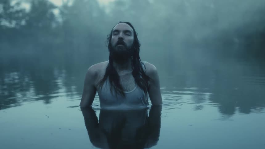 A man swimming in a rippling lake on a misty morning