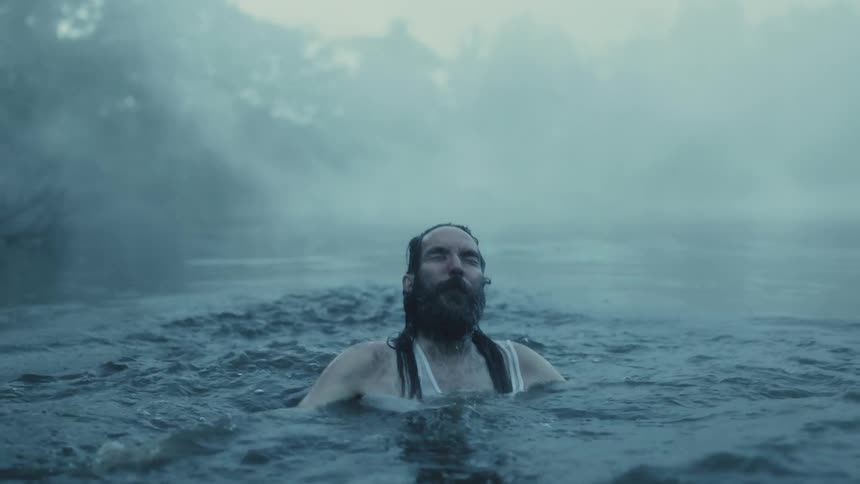 A man popping up from lake water while swimming on a foggy day