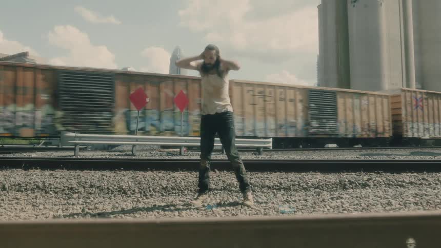 A man is standing by a train in a downtown city