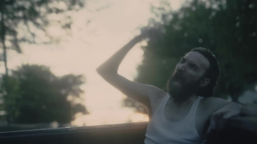 A man pumps his fist and screams as he rides in the back of a pickup truck